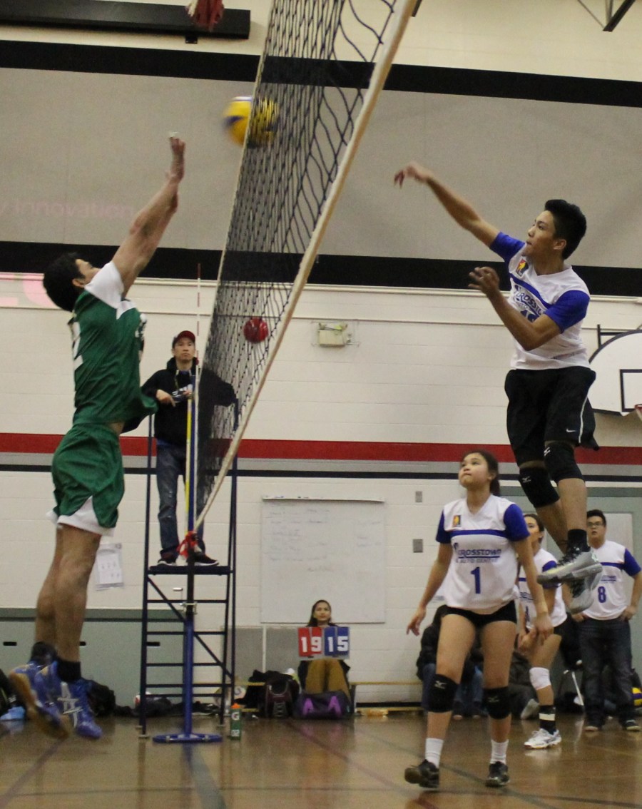 White's Trecito Gansan (right) delivers a spike against a blocking Alvin Lomboy of Green in the 2014 PSA-Crosstown Auto Coed volleyball league final, March 30, at the St.Clement Catholic School.(Photo by Moses Billacura/pinoy edmonton news)